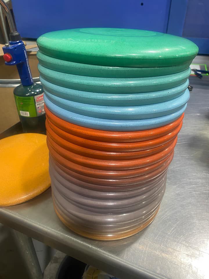 Stack of blank Hemp Frisbees or Hemphrisbees in Orange, Purple, Saphire, Brozne, Tangerine on countertop .