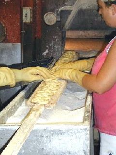 two woman in pink tank top placing hand rolled sourdough Hempzels(tm) on a pretzel piel and getting ready to put in oven.