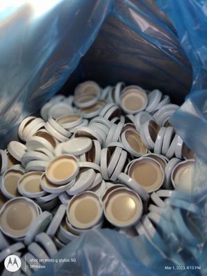 Open Blue Bag in Card board box filled with white lids to secure the white mini plastic jars.