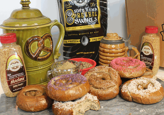 Green ceramic with lid and pretzel sign, black and gold bag for swirled soft pretzels laying in front salted.