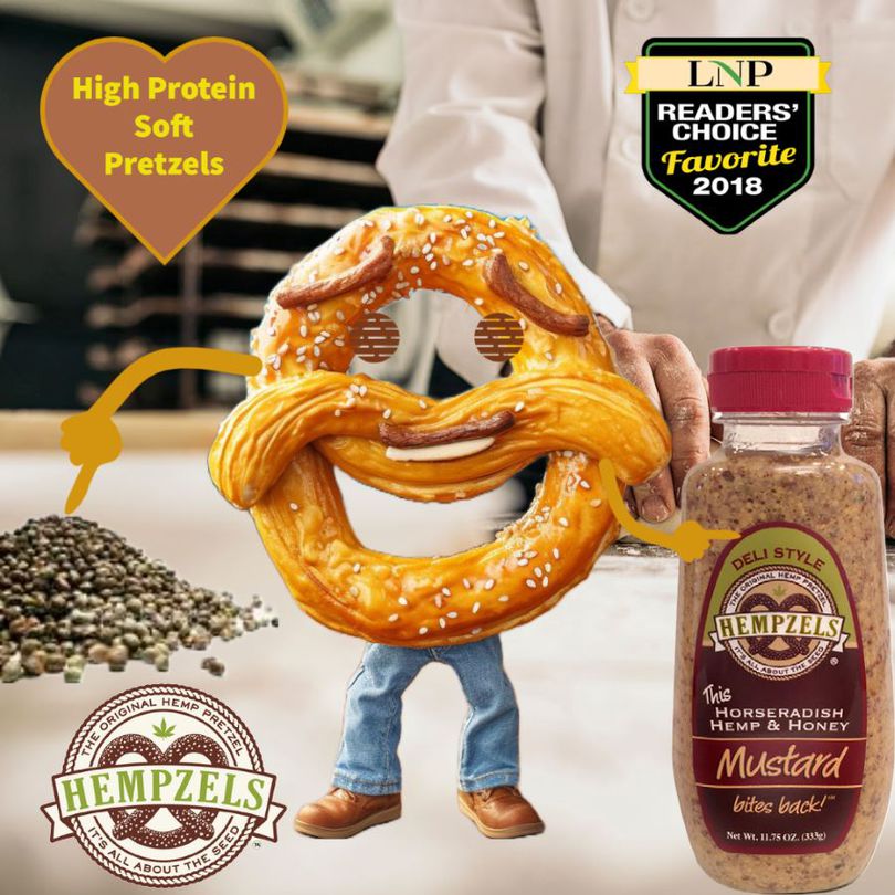 Smiling pretzel circle with hemp seed to the left & mustard to the right with a baker behind him.