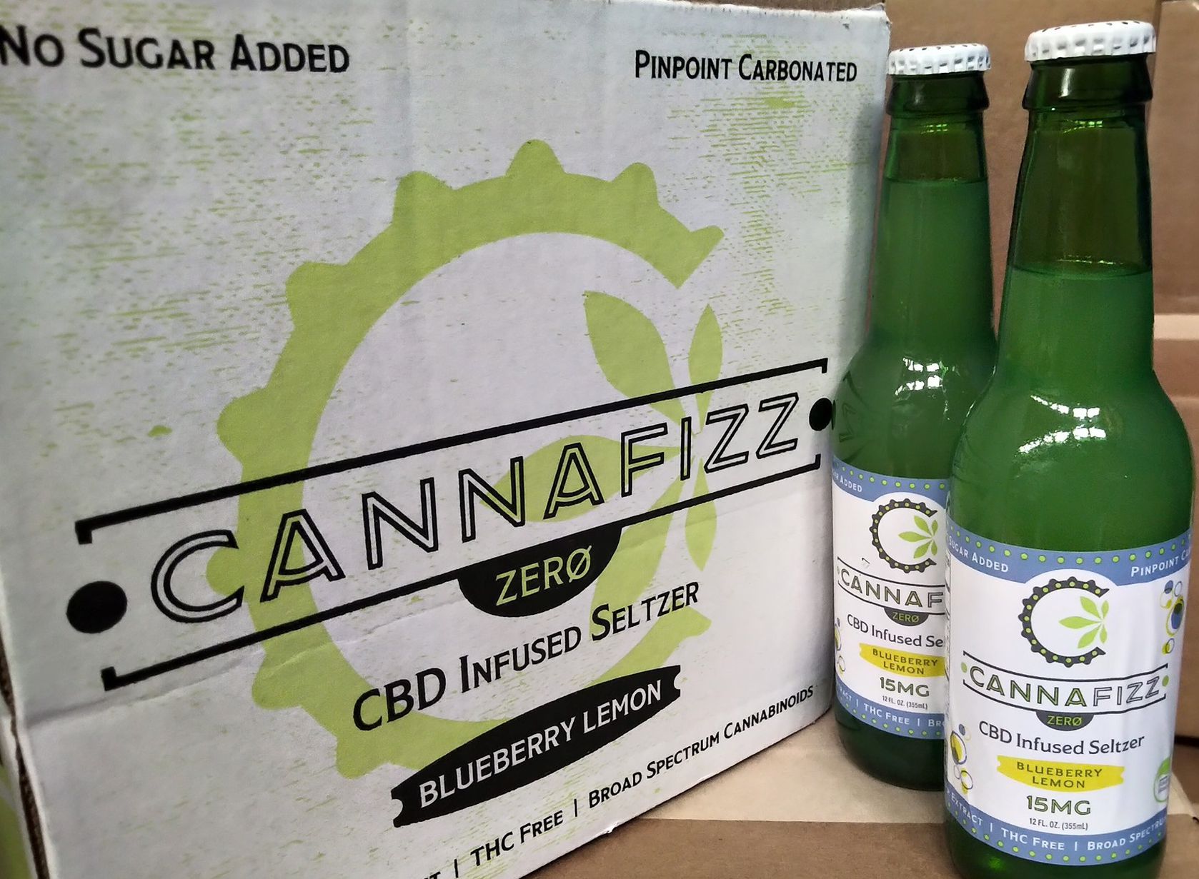 2 Green Glass Bottles of Cannafizz seltzer water next to case box