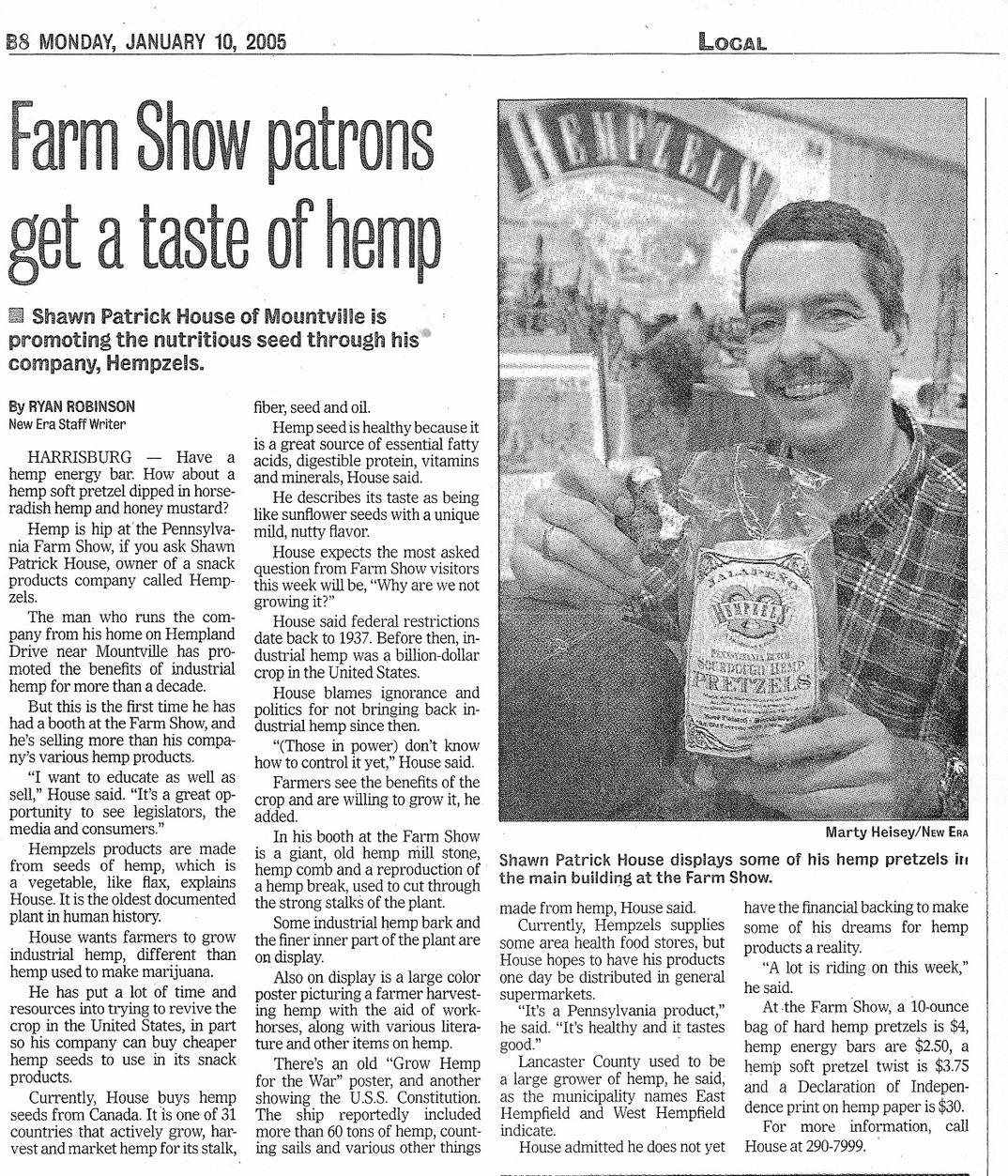 Black & White Newspaper article of Shawn House holding Sourdough Hemp Pretzel in Farm Show booth
