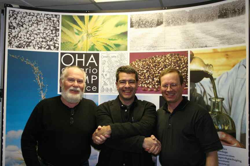 Shawn House in black hemp suit stands in the middle with OHA leaders shaking both hands of men standing on either side.