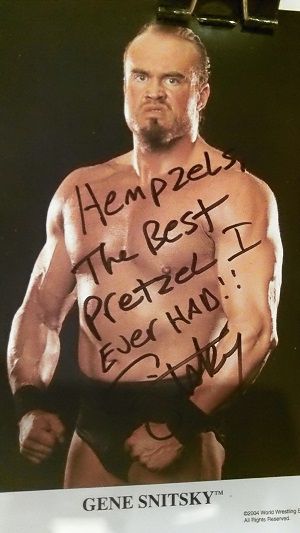 Wrestler Gene Snitsky posed in shorts flexing muscles & written autographed best pretzels ever.