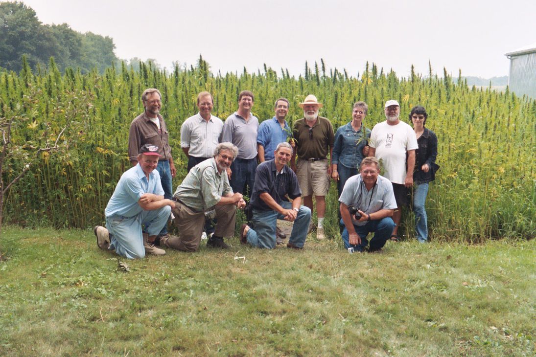 Shawn House surrounded by Canadian Ontario Hemp Alliance attendees in front of large hemp field.