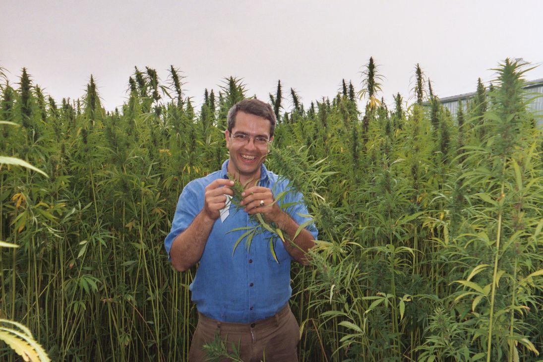 Shawn House in blue hemp short sleeve shirt holding grains of hemp or chanvre in french.