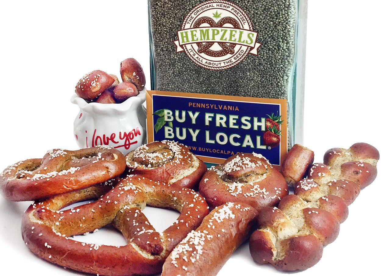 Big jar of hemp seed and mustard surrounded by high protein soft pretzels Hempzel(tm) logo & QR codes..