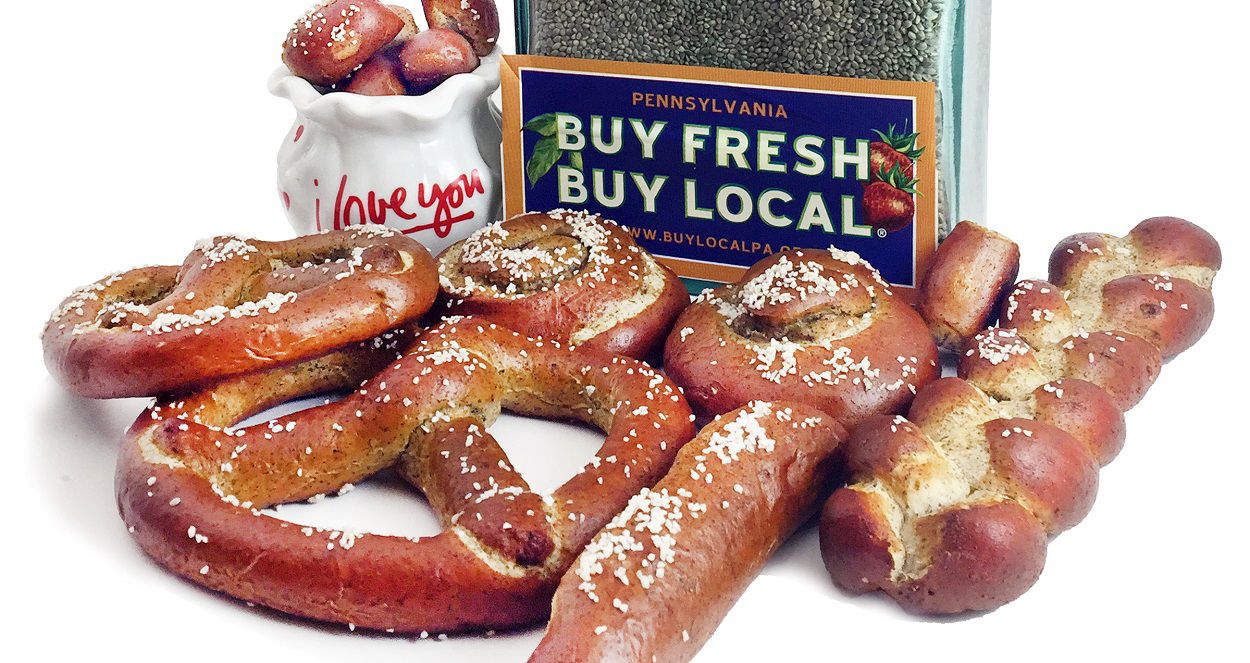 Hot Soft Pretzels in the traditional shape, a rolls, braid, rod or nuggets in front of hemp seed with a bumper sticker buy fresh buy local.
